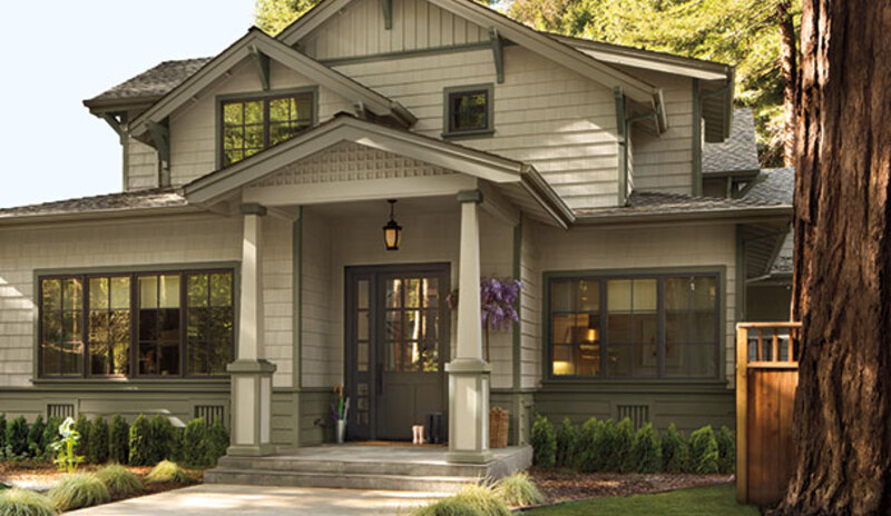 A gray-painted house with green-painted accents and hedges lining the walkway.