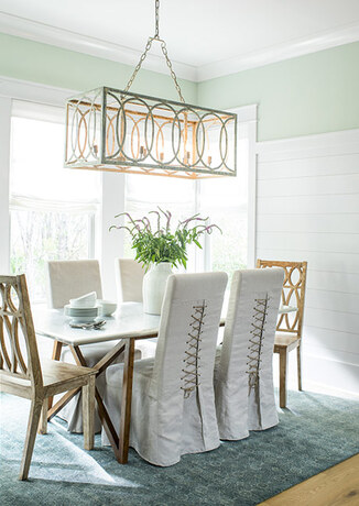 A delicate green-painted dining room with pendant light and teal rug.