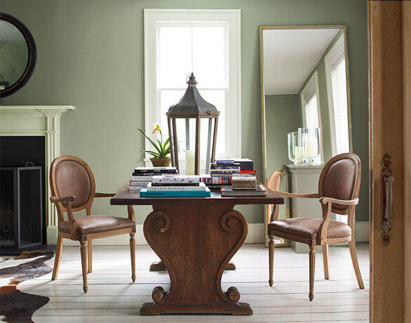 A green-painted living room with ornate wooden table and vintage accents.