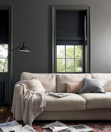 Dark gray living room with matching window trim featuring a tan couch with three pillows. Dark gray living room with matching window trim featuring a tan couch with three pillows.