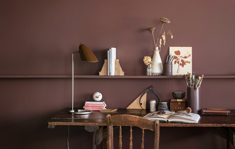 An office with brown-painted walls, a long wooden shelf, and a matching wooden desk and chair An office with brown-painted walls, a long wooden shelf, and a matching wooden desk and chair