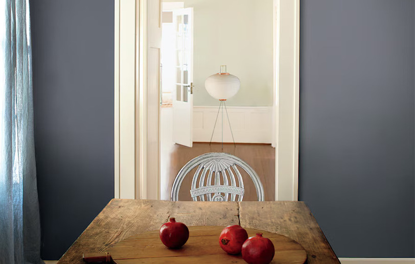 Rustic plank table with gray-blue wall and pomegranates